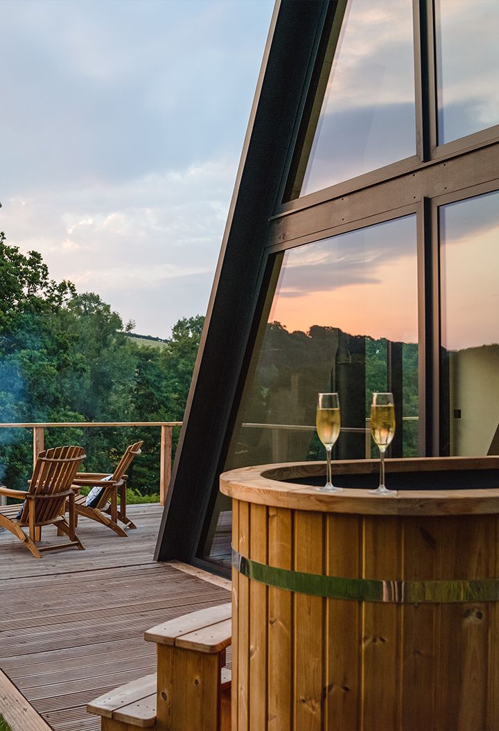 Hot tub on decking with two glasses, outdoor seating and fire