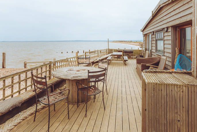 Sandy Toes Beach House exterior and decking with outdoor seating and a view of the sea 